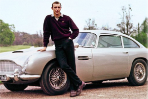 A man standing in front of his old style car, James Bond