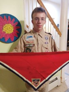 A boy standing in his boy scouts uniform holding his neckerchief.