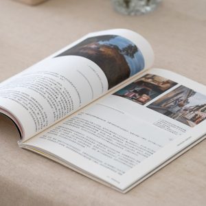 An open book on a beige table, featuring Chinese text and images of landscapes and street scenes on its pages.